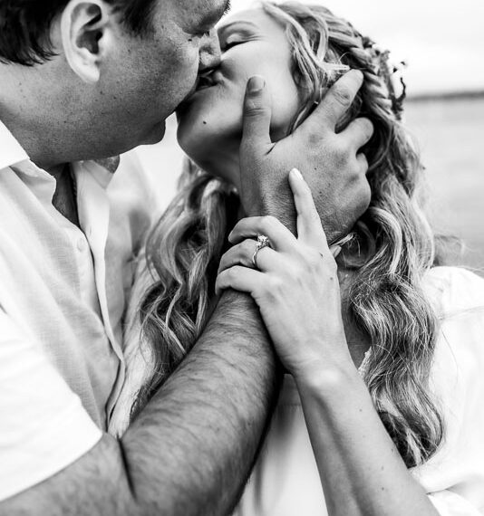 Engaged couple kissing in black and white.