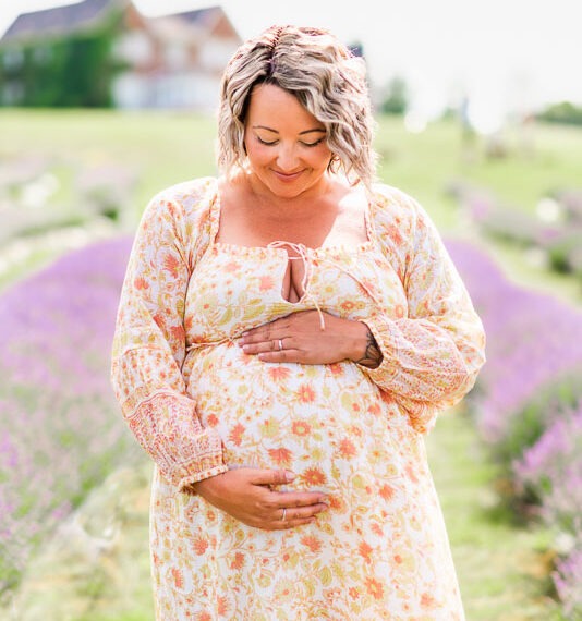 Pregnant woman holding her belly in a lavender field.