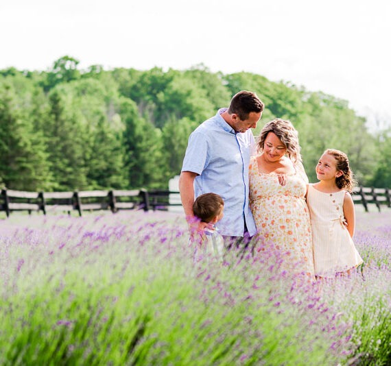 Pregnant woman with her spouse and children in a lavender field.