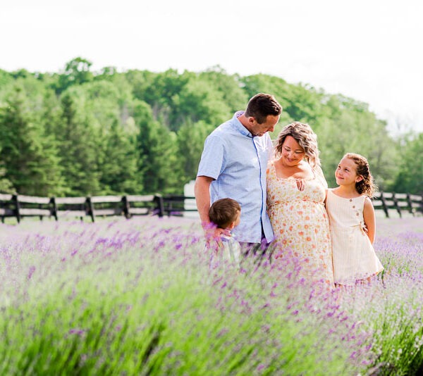 Pregnant woman with her spouse and children in a lavender field.