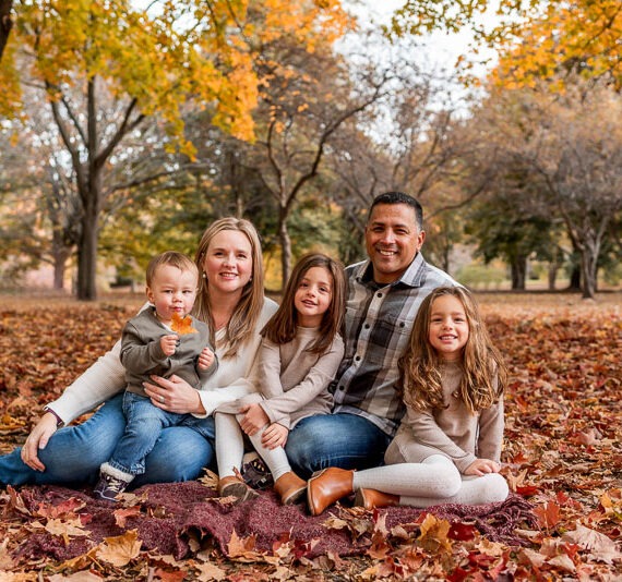 Family sitting in the woods during the fall.