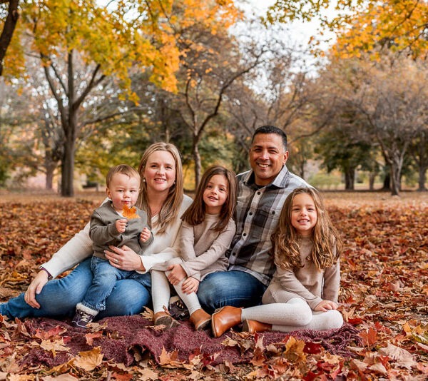 Family sitting in the woods during the fall.