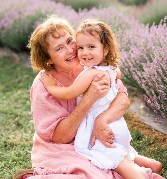 Grandmother and granddaughter in a lavender field hugging.