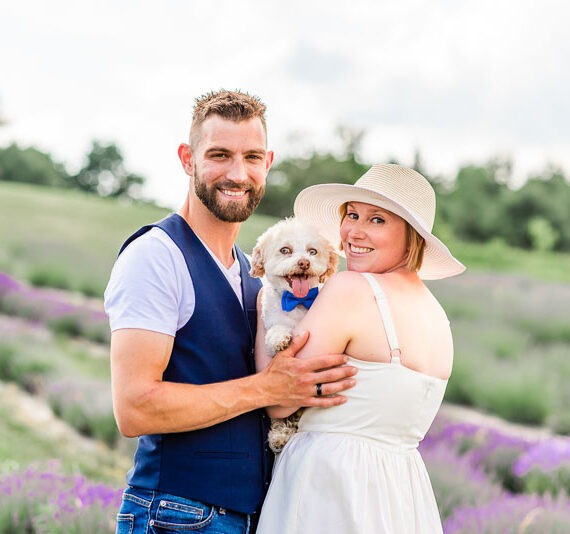 Couple in a lavender field with their small white dog.