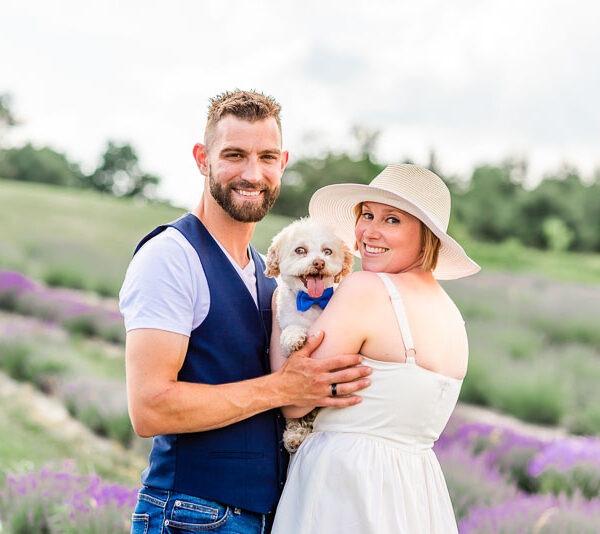 Couple in a lavender field with their small white dog.