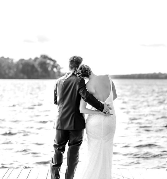 Newlyweds looking out at a lake from a dock.