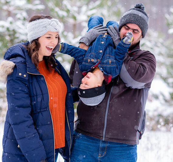 Parents playing with their son in the snow.