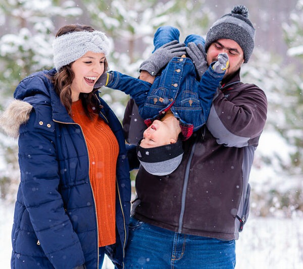 Parents playing with their son in the snow.