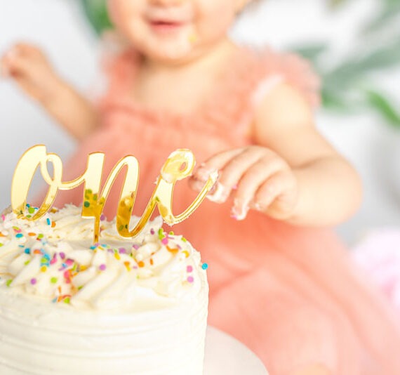 Close-up of baby with their first birthday cake.