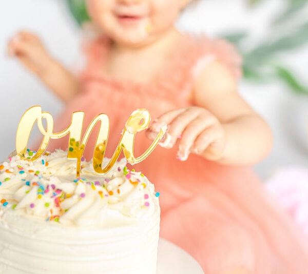 Close-up of baby with their first birthday cake.