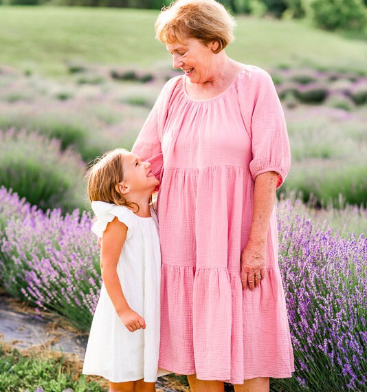 Grandmother smiling down at her granddaughter in a lavender field.