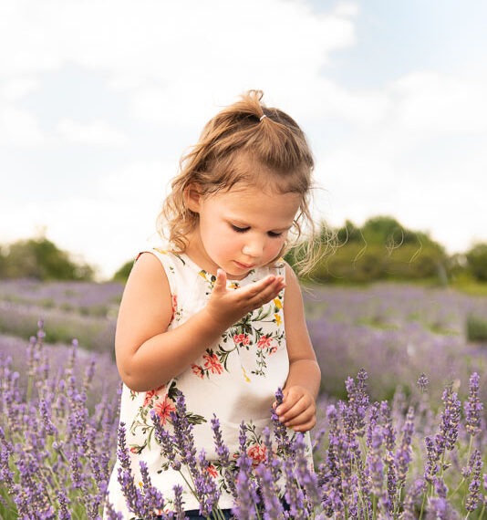 Little girl studying a piece of lavender in her hand.