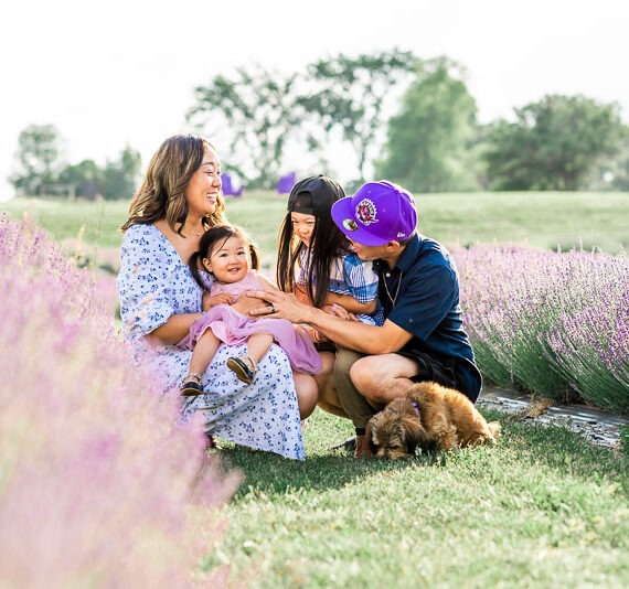 Family sitting together in a lavender field with their dog.